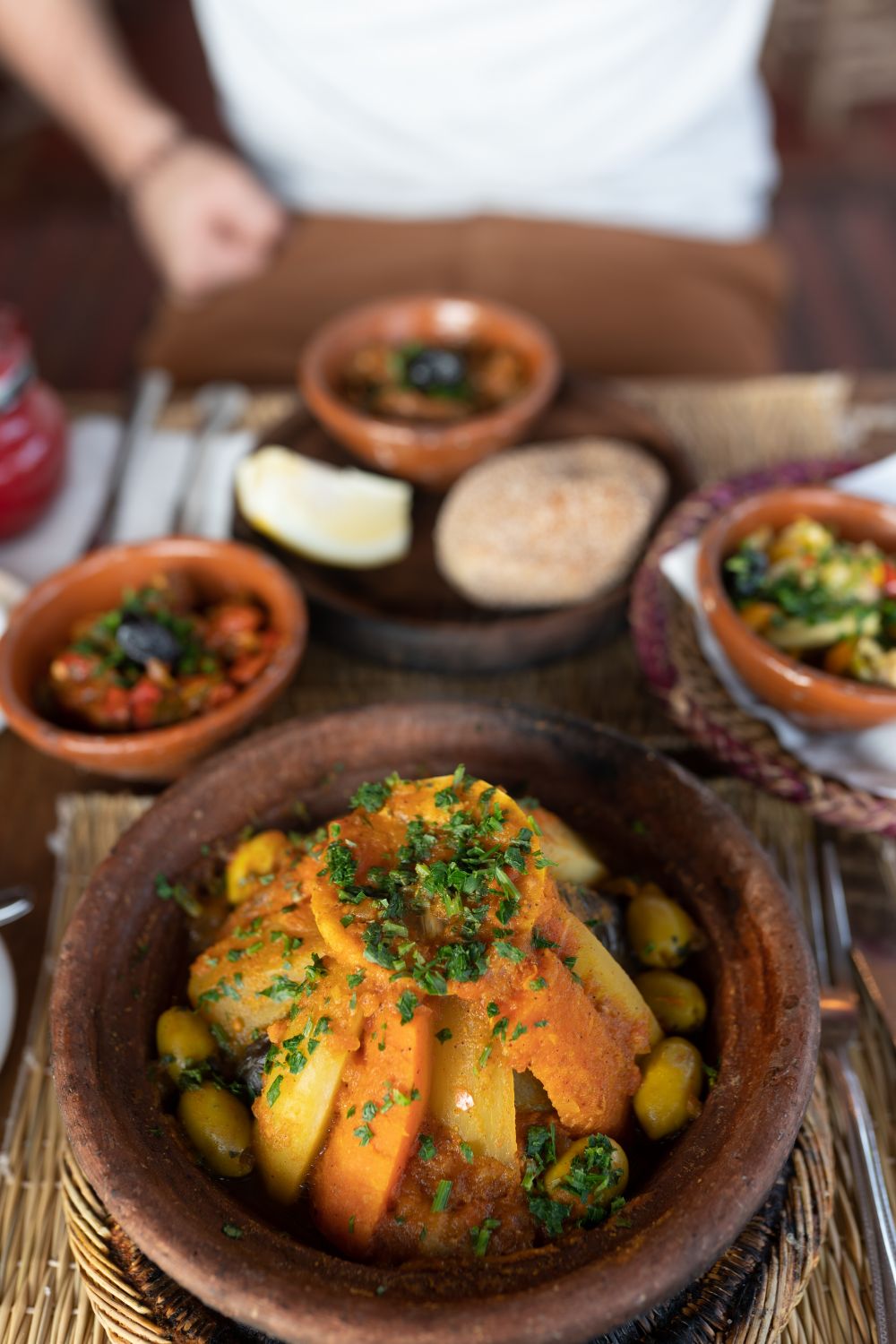 Een tajine met groenten en olijven op een tafel vol kleine gerechtjes